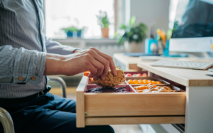 Person grabbing a healthy snack from their office desk drawer