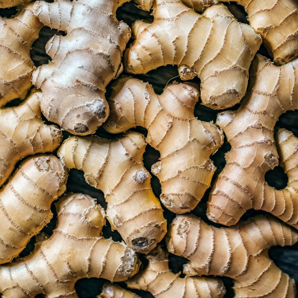 A close-up of fresh ginger root, showing its knobby texture and pale yellow color